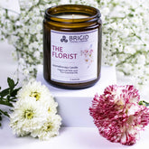 the florist premium aromatherapy grade essential oil candle candles by brigid trading company washington state united states ireland seven ounces kitsap therapy therapeutic benefits natural health white babys breath background with white flowers and pink flowers in the foreground candle in center wedding gifts for her mothers day present ideas delicate floral scents feminine for him